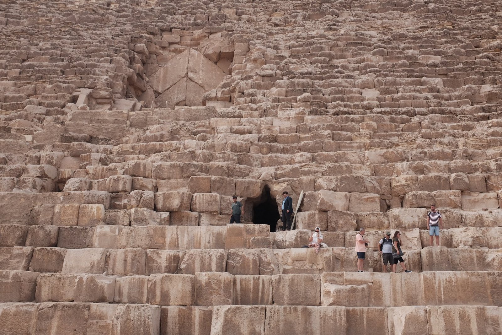 A group of people standing over the massive stones near the entrance of the Great Pyramid.