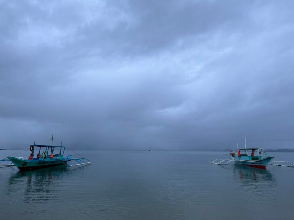 Boats anchored at Port Barton Beach against a cloudy sky.