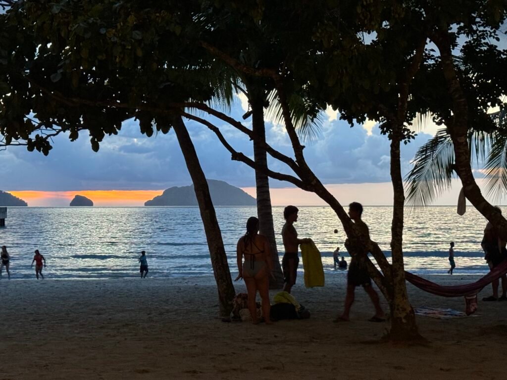 Beachgoers enjoying the sea and the sunset view at Lio Beach, El Nido, Philippines.