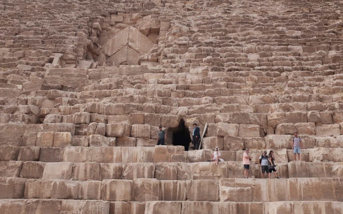 A group of people standing over the massive stones near the entrance of the Great Pyramid.